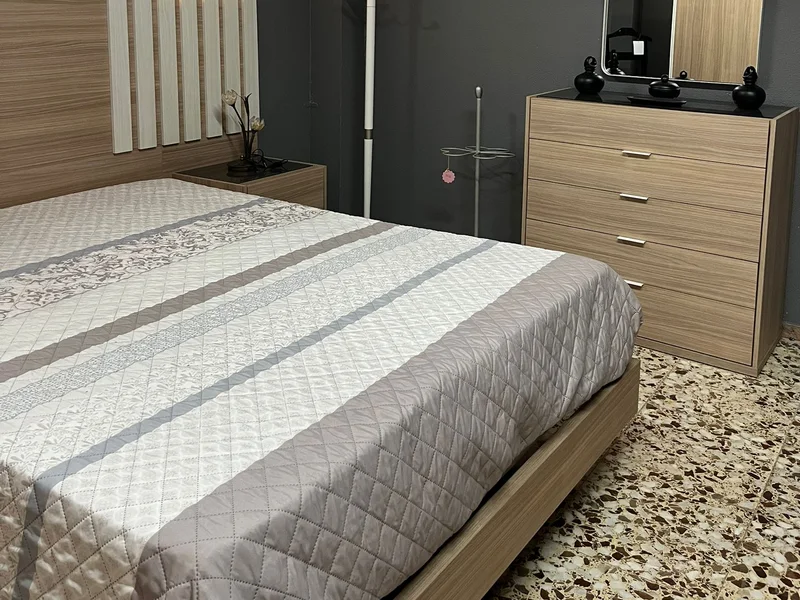 Dormitorio de matrimonio expuesto con cómoda, espejo y mesitas a juego.