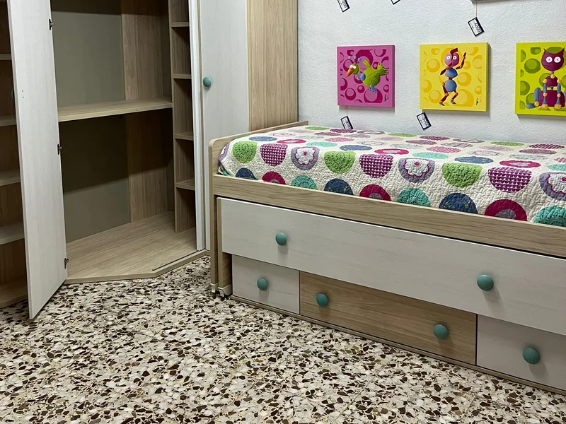 Dormitorio juvenil con cama compacta de cajones, armario y cuadros infantiles.